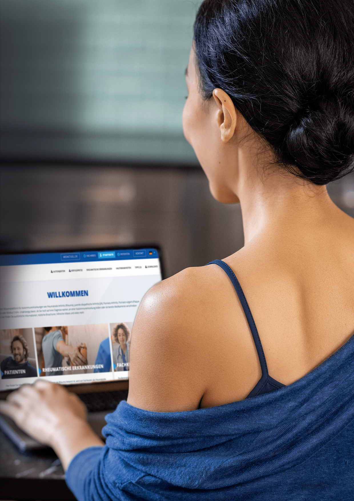 medac metoject Keyvisual: Frau mit dunklen Haaren, die eine blaue Bluse trägt und auf einen Laptop-Bildschirm mit einer deutschen Webseite über rheumatische Erkrankungen schaut.