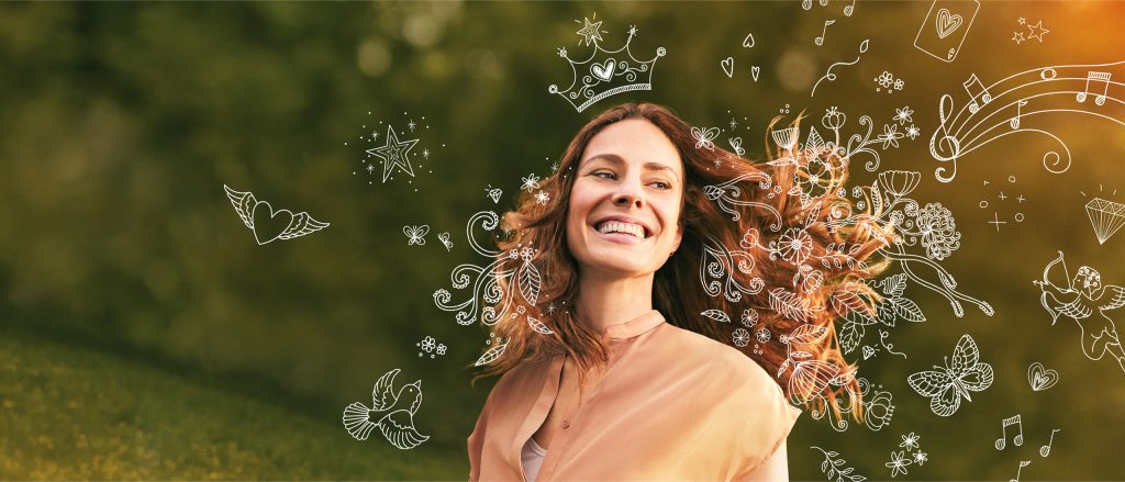 Bio-H-Tin Keyvisual: Haare mit Wow. Lächelnde junge Frau mit wehenden roten Haaren vor einem verschwommenen grünen Hintergrund, umgeben von weißen, handgezeichneten Illustrationen von Blumen, Schmetterlingen und Herzen.