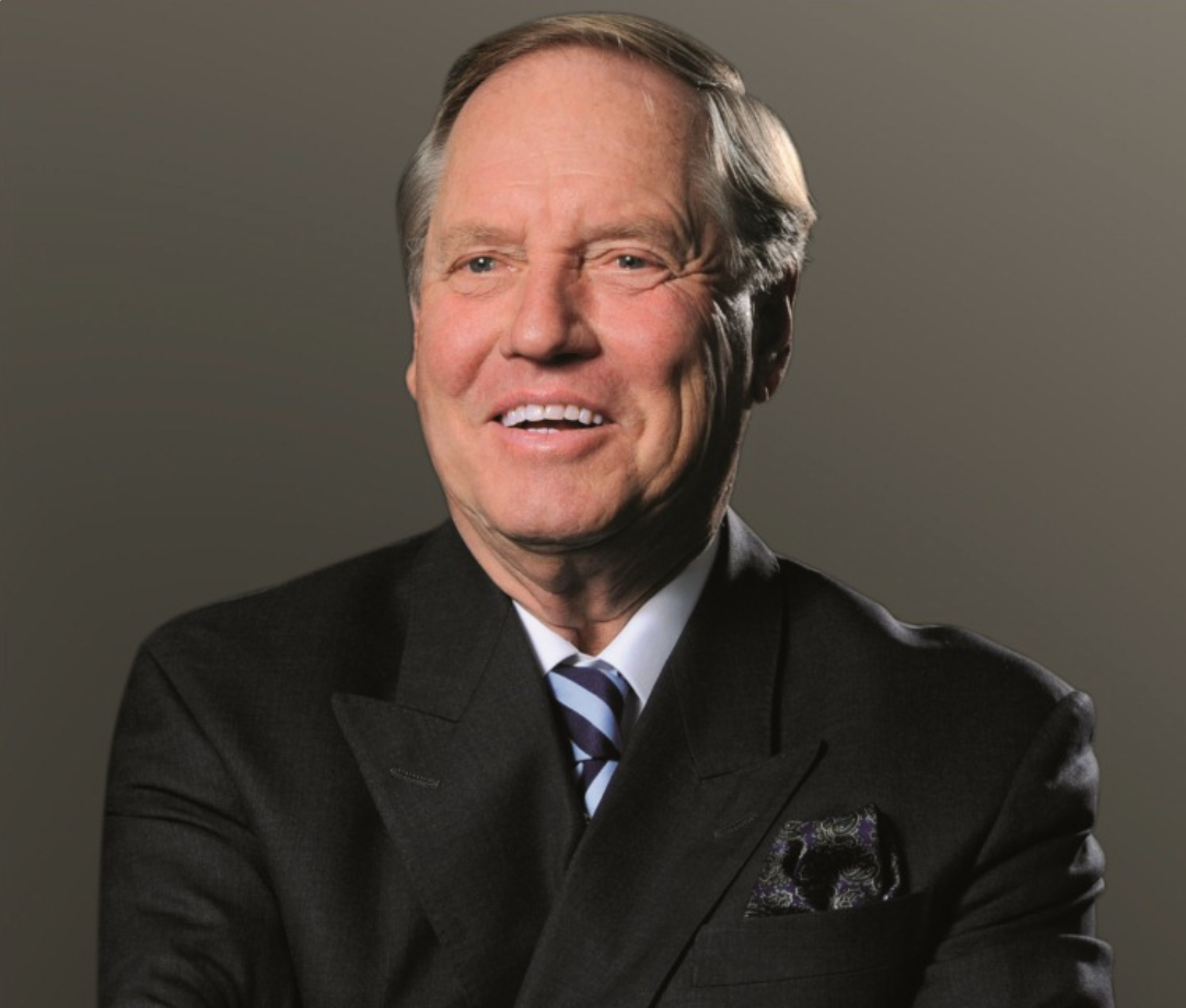 Dieter Haack in dunklem Anzug und gestreifter Krawatte lächelnd vor hellem Hintergrund.