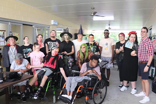 A large group of people posing indoors in various elaborate Halloween costumes and makeup.