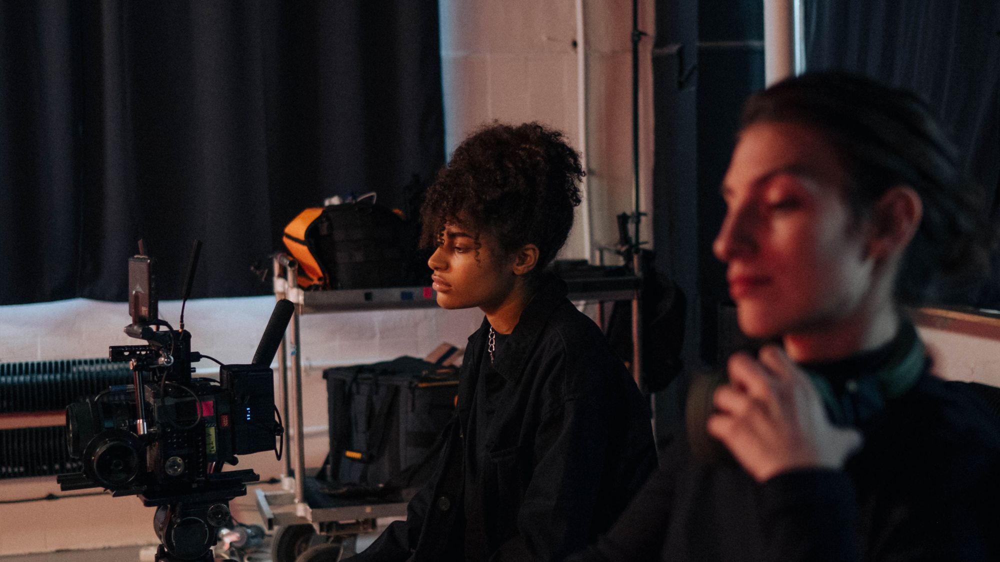 Camera operator adjusting a cinema camera on a testimonial interview set before recording