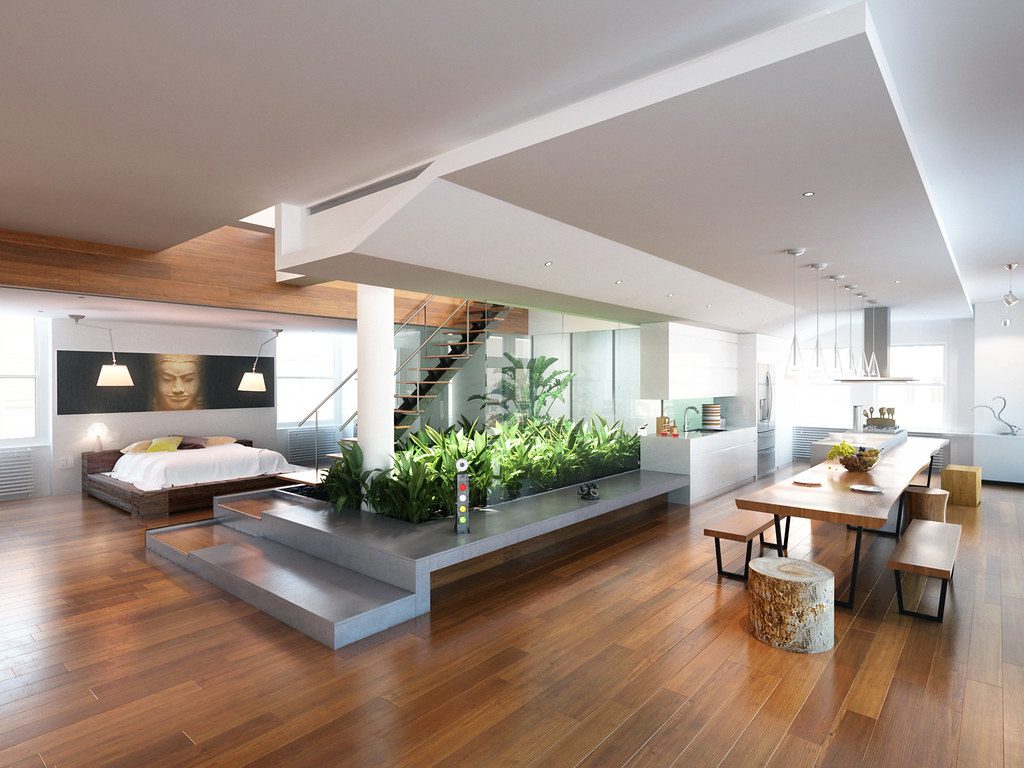 Open plan modern home interior with wood floors, a garden planter, and a dining table under pendant lights.