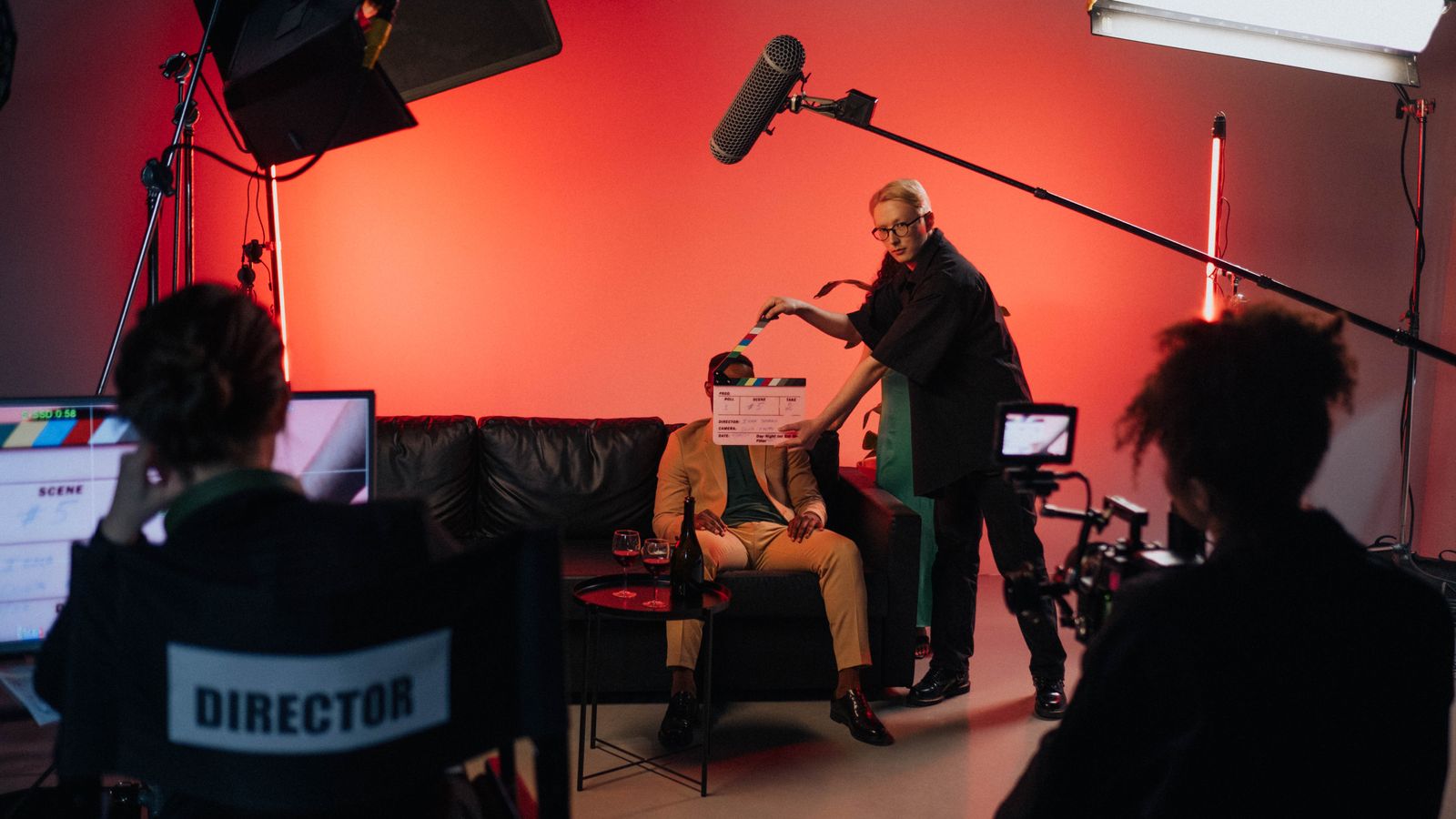 A behind-the-scenes look at a filming crew setting up a scene indoors with lighting equipment.