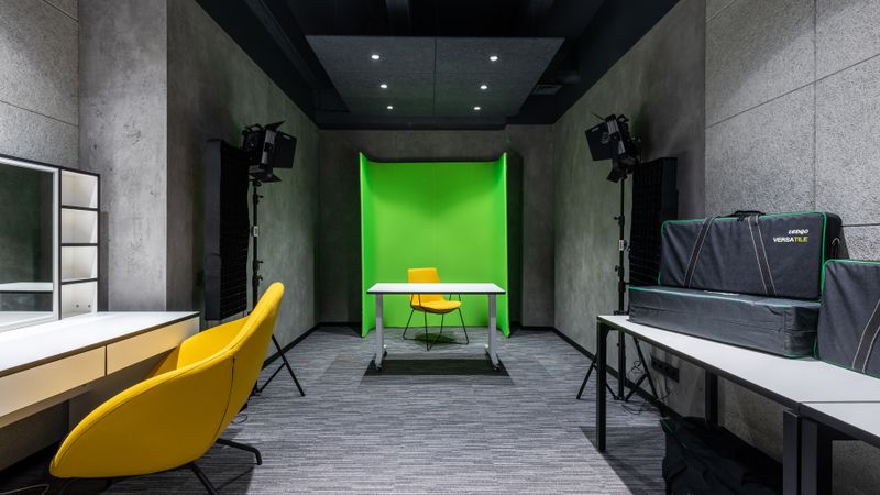 Yellow chair at table placed near green background in spacious contemporary studio with lightning supply and...