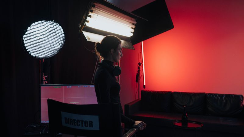 A director in a studio setting with lighting and equipment, creating a cinematic atmosphere.