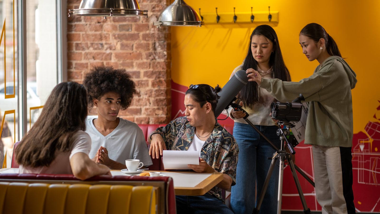 A diverse film crew collaborating in a cozy cafe setting with cameras and microphones.