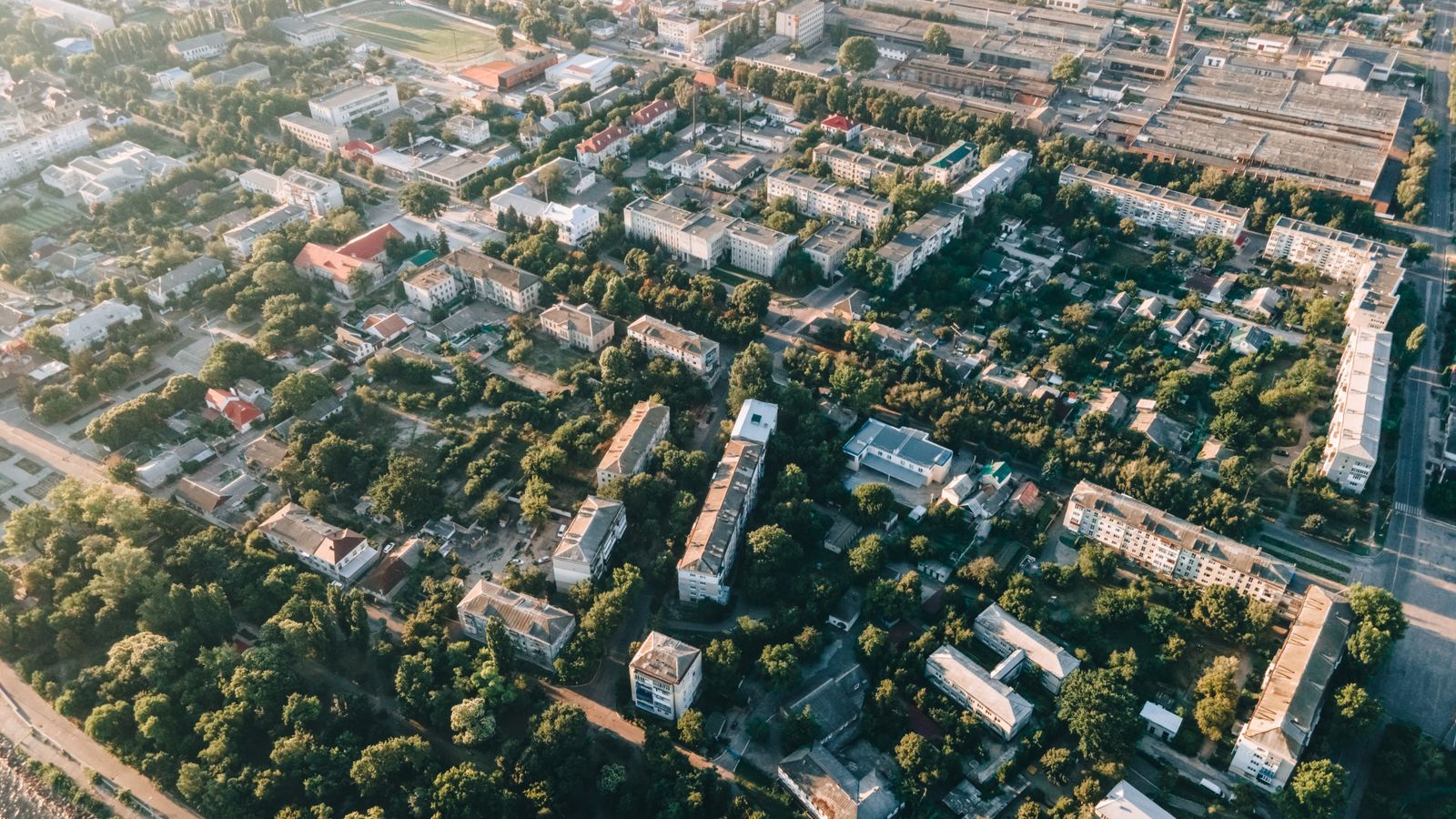 Aerial view of urban cityscape with residential buildings, roads, and greenery.
