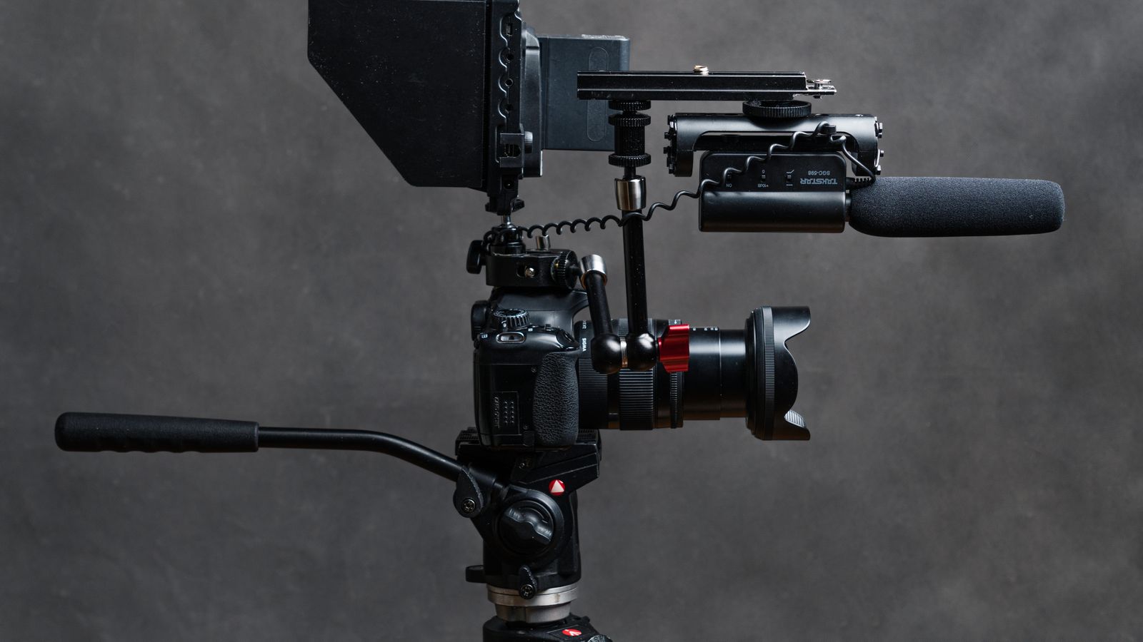 Close-up studio shot of a DSLR camera with video accessories including a microphone and tripod.