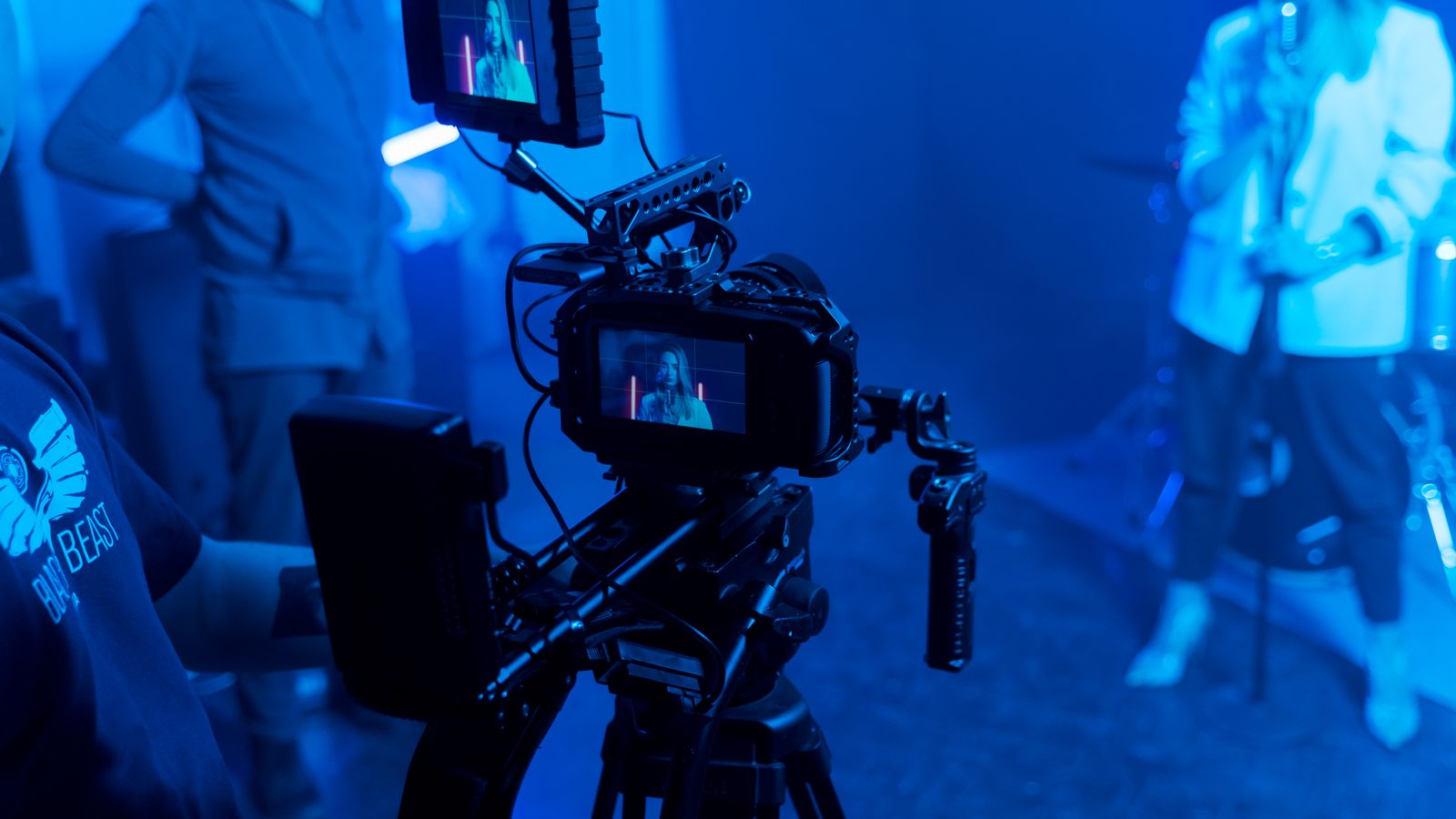 Behind the scenes of a music video recording with professional film equipment and studio lighting.