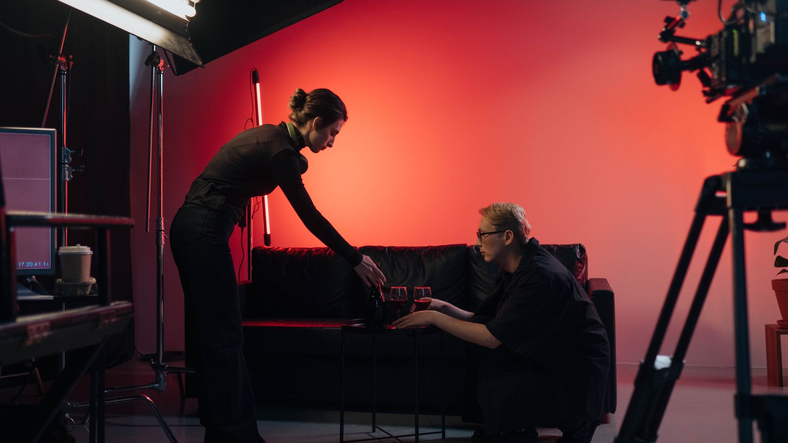 Behind-the-scenes view of a film crew in action, setting up a studio scene with lighting and equipment.