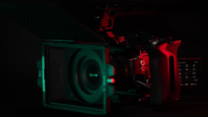 Close-up of a cinema camera rig with striking neon lighting, perfect for videography setups.