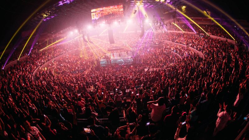 Vibrant crowd enjoying a live concert in a bustling Manila arena at night.