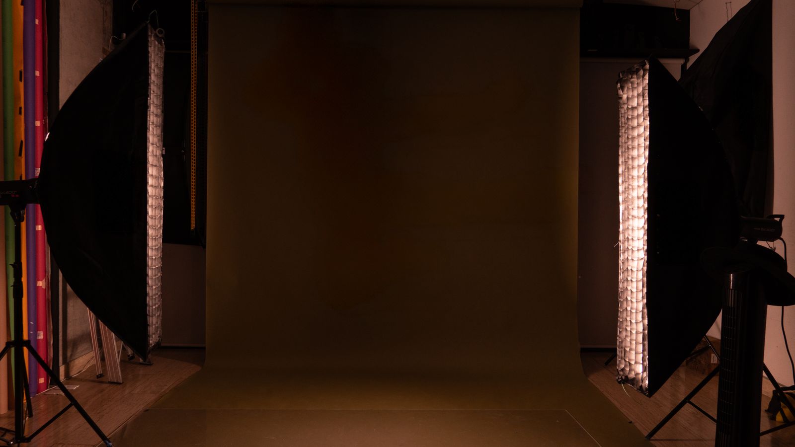 A sleek and modern photography studio setup featuring a mocha backdrop and professional lighting equipment.