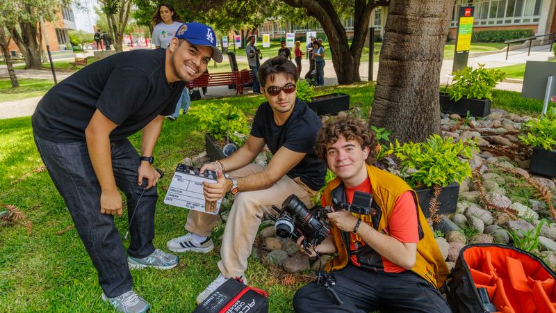 A film crew setting up camera equipment in a park, preparing for an outdoor shoot.