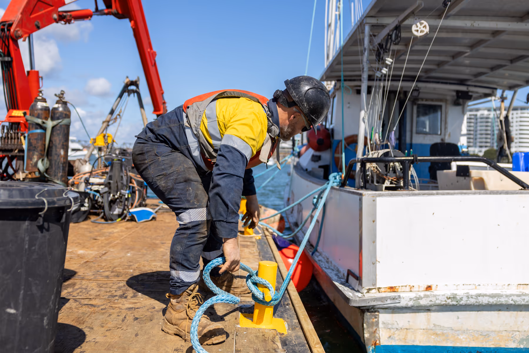 Man connecting boat to pier. 