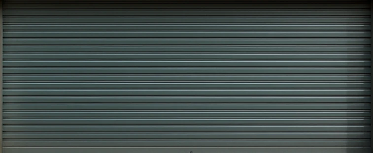 Closed grey metal roller garage door with horizontal ridges.