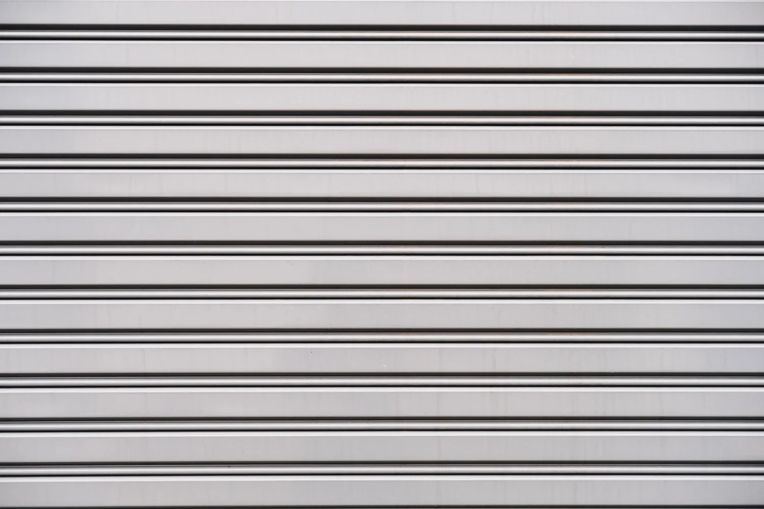 Closed gray metal shutter with horizontal ridges.