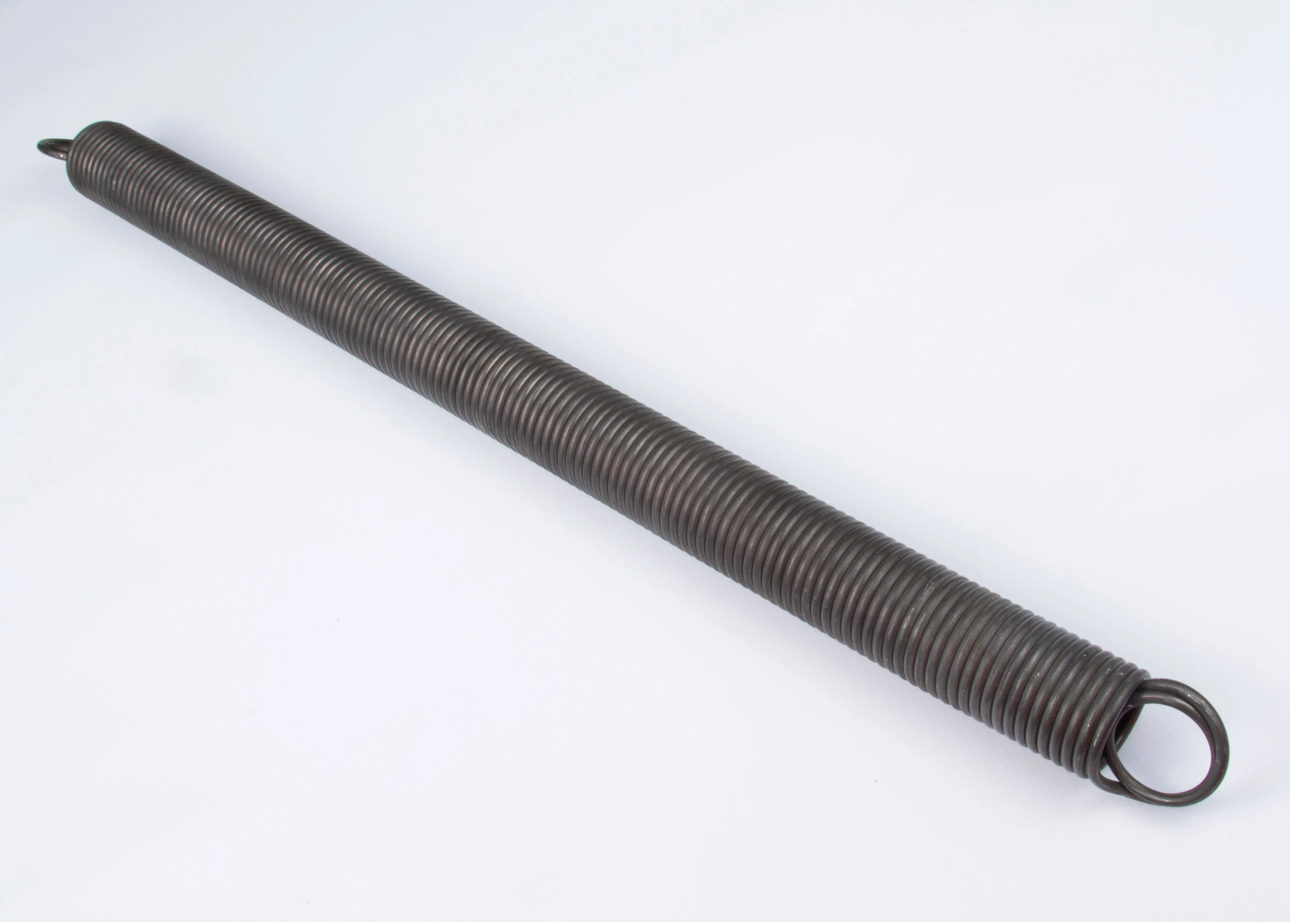 Close-up of a coiled metal tension spring with looped ends on a white background.