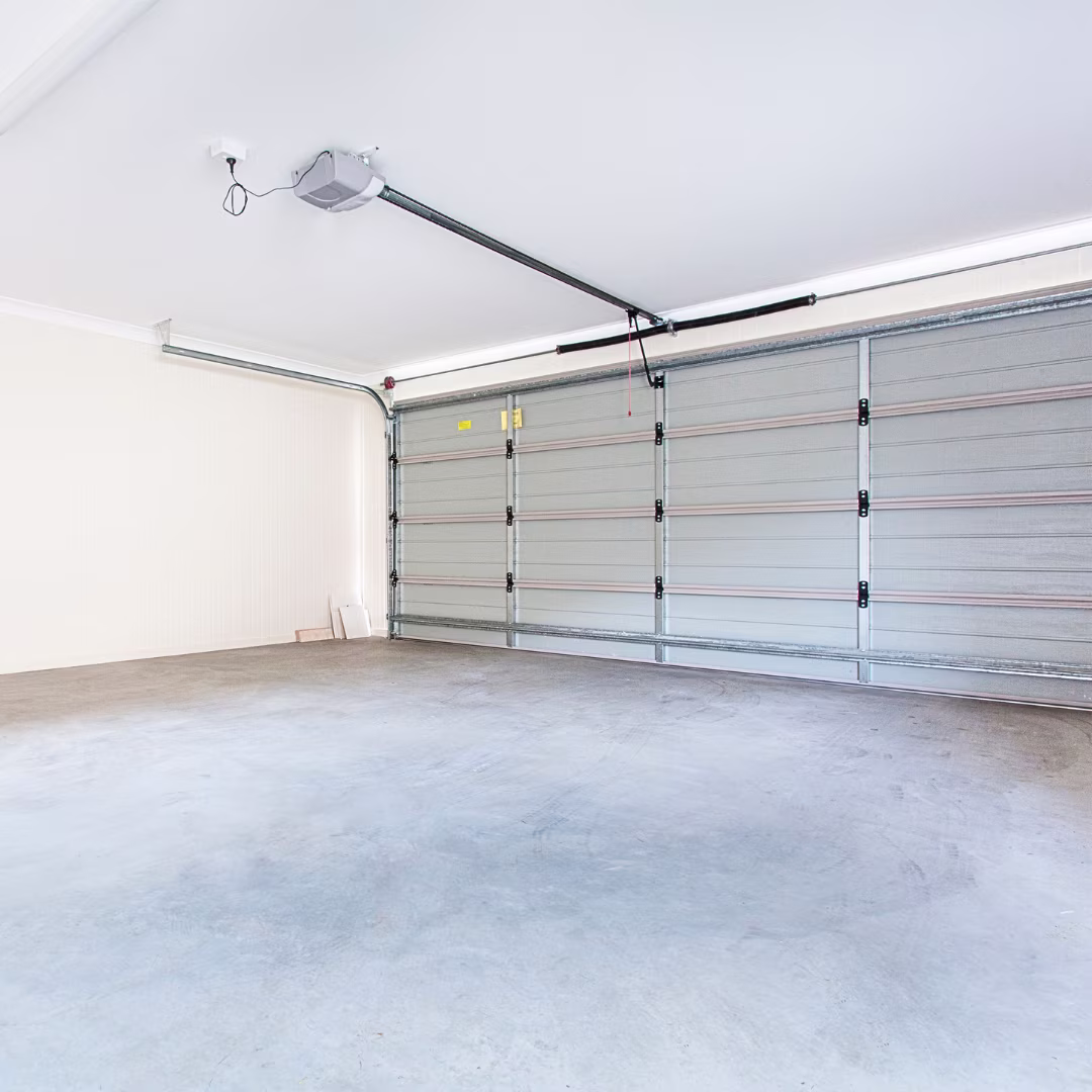 Empty garage interior with closed gray sectional garage door and concrete floor.