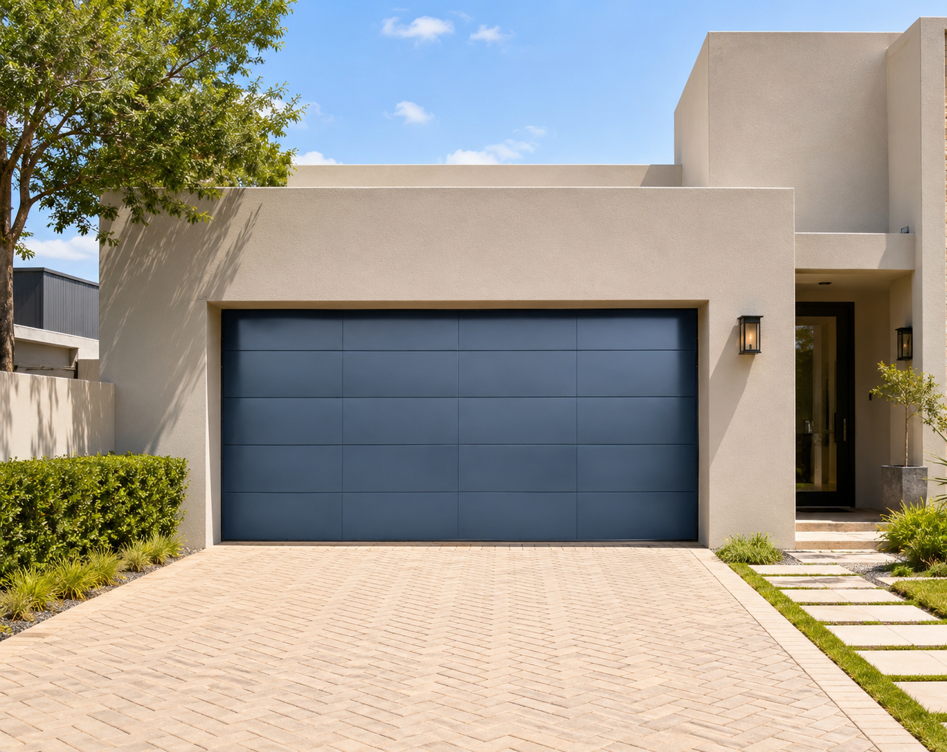 Modern beige house with a large blue garage door and a paved driveway under a sunny sky.