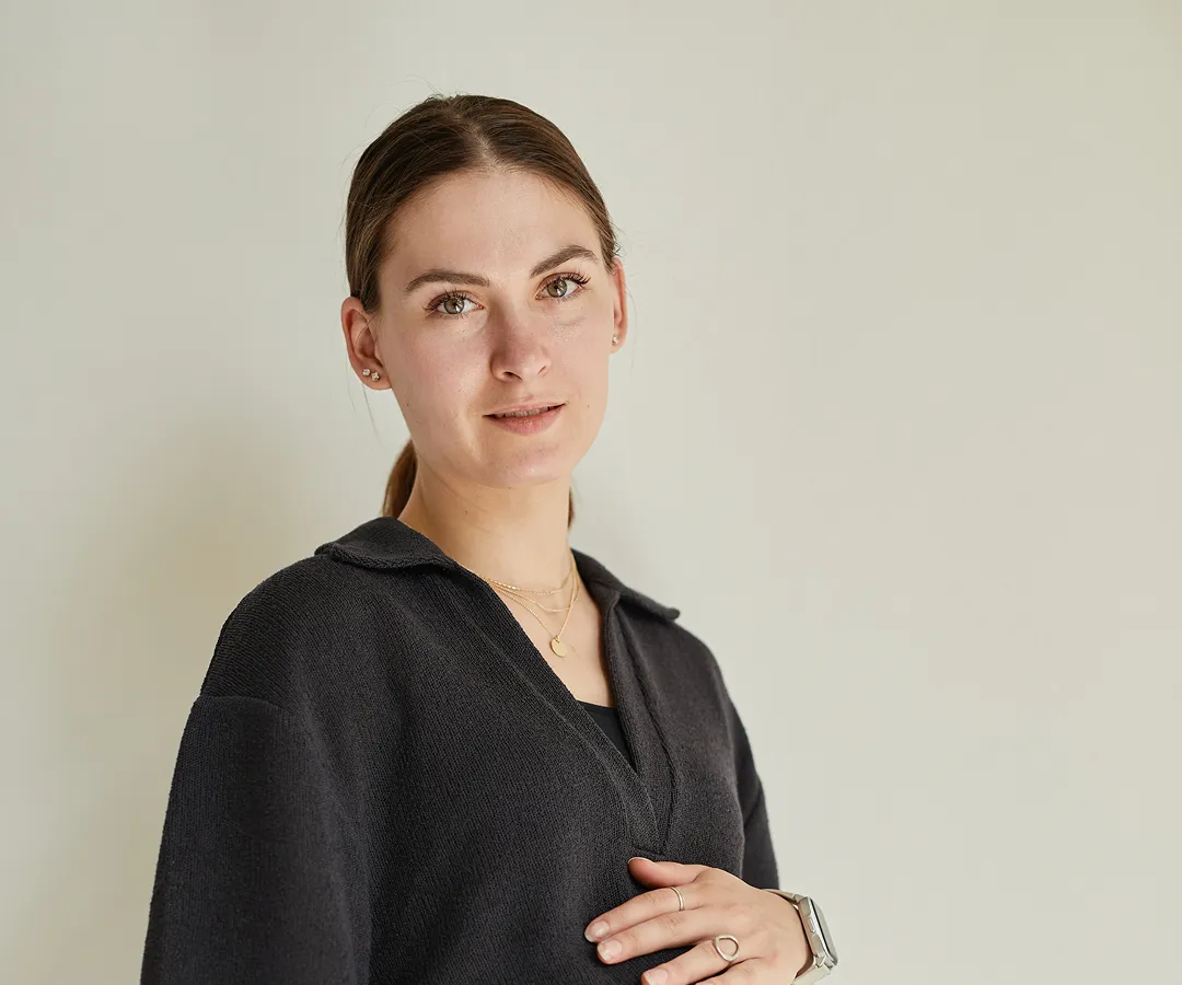 A woman standing in front of a white wall.