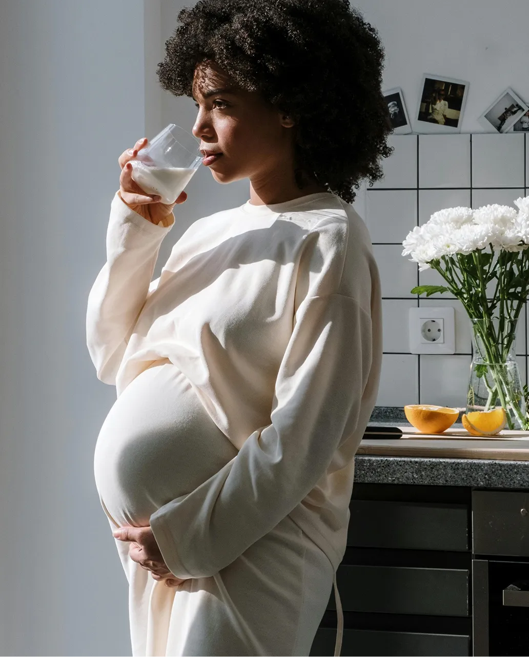 A pregnant woman drinking a glass of milk.