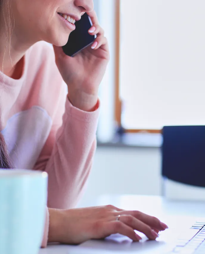 A woman sitting at a desk talking on a cell phone.