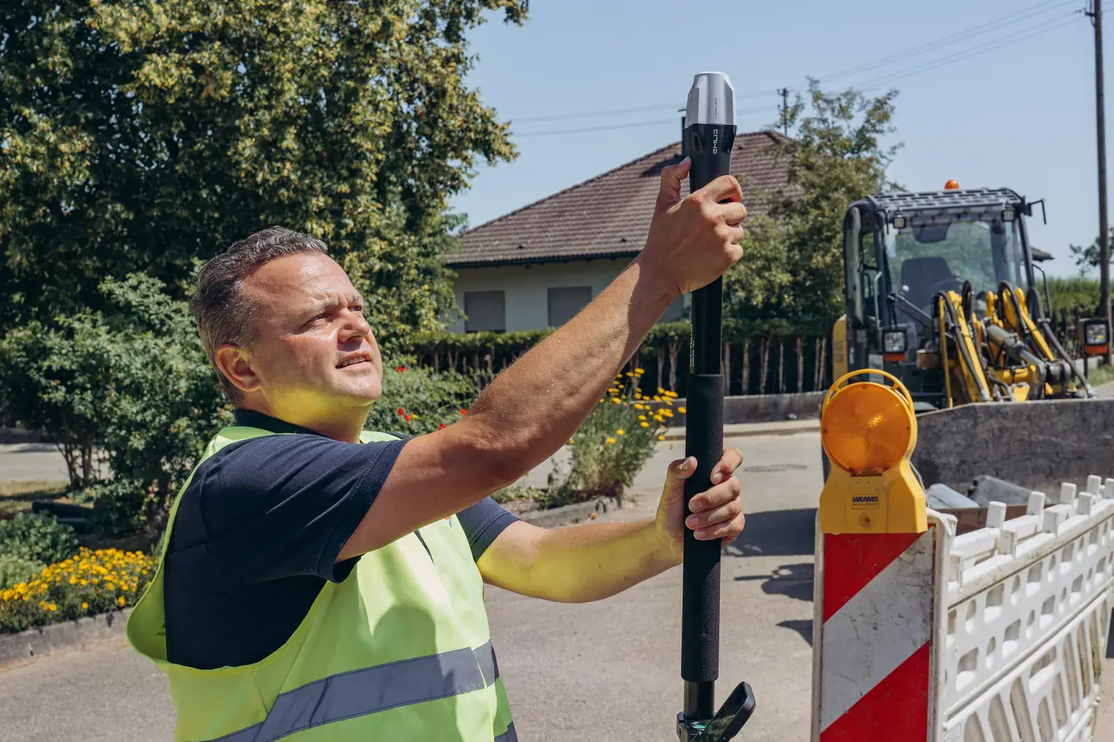 Vermesser mit GPS-Rover am Lotstab auf einer Straßenbaustelle