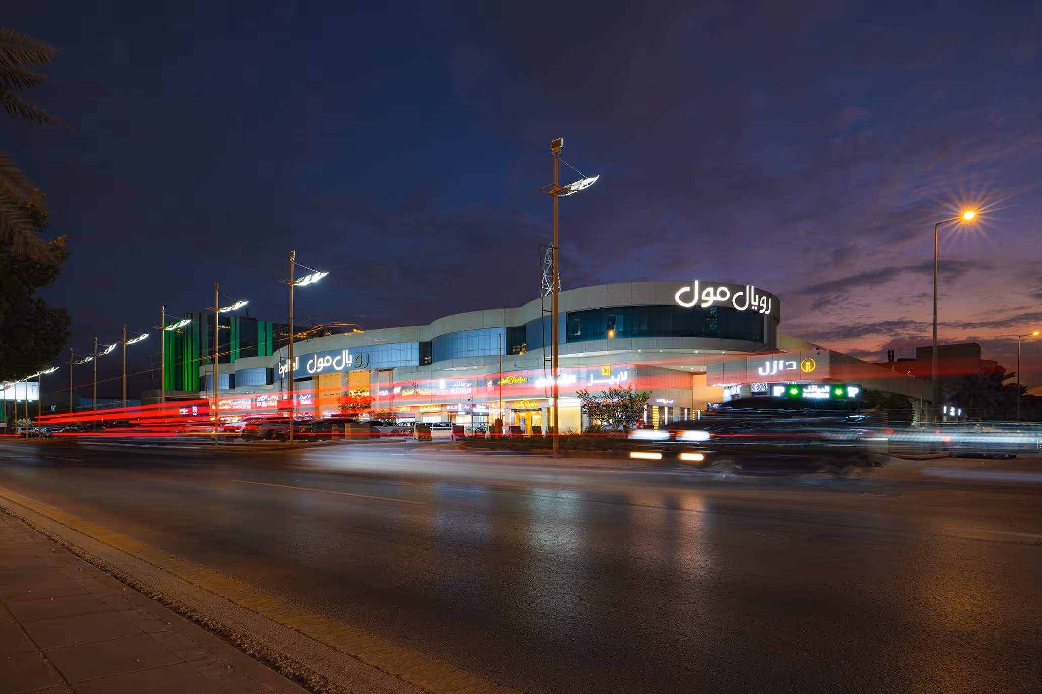 Royal Mall building illuminated at dusk with light trails from passing cars on the road in front.