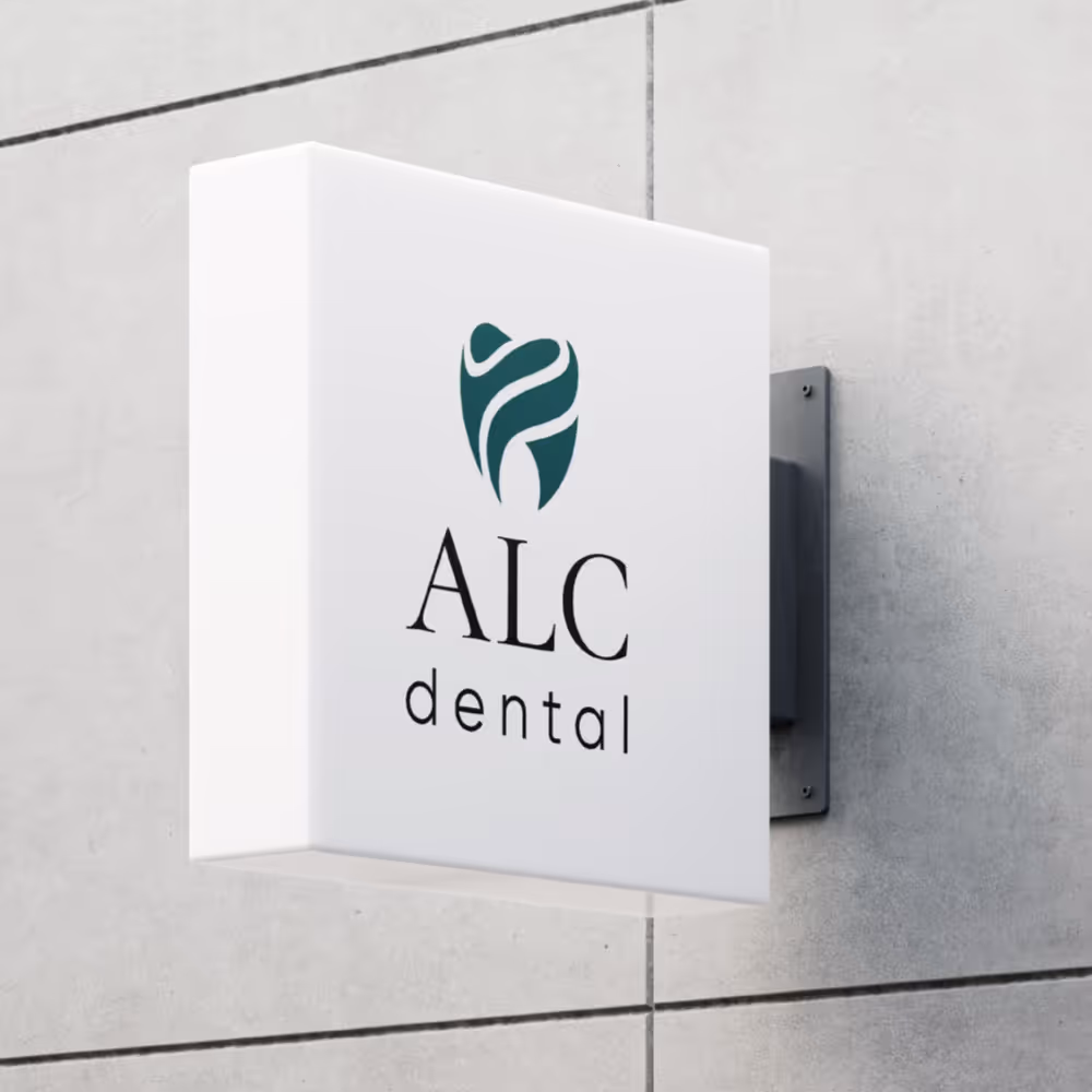Wall-mounted white sign with a stylized teal tooth logo and the text 'ALC dental'.