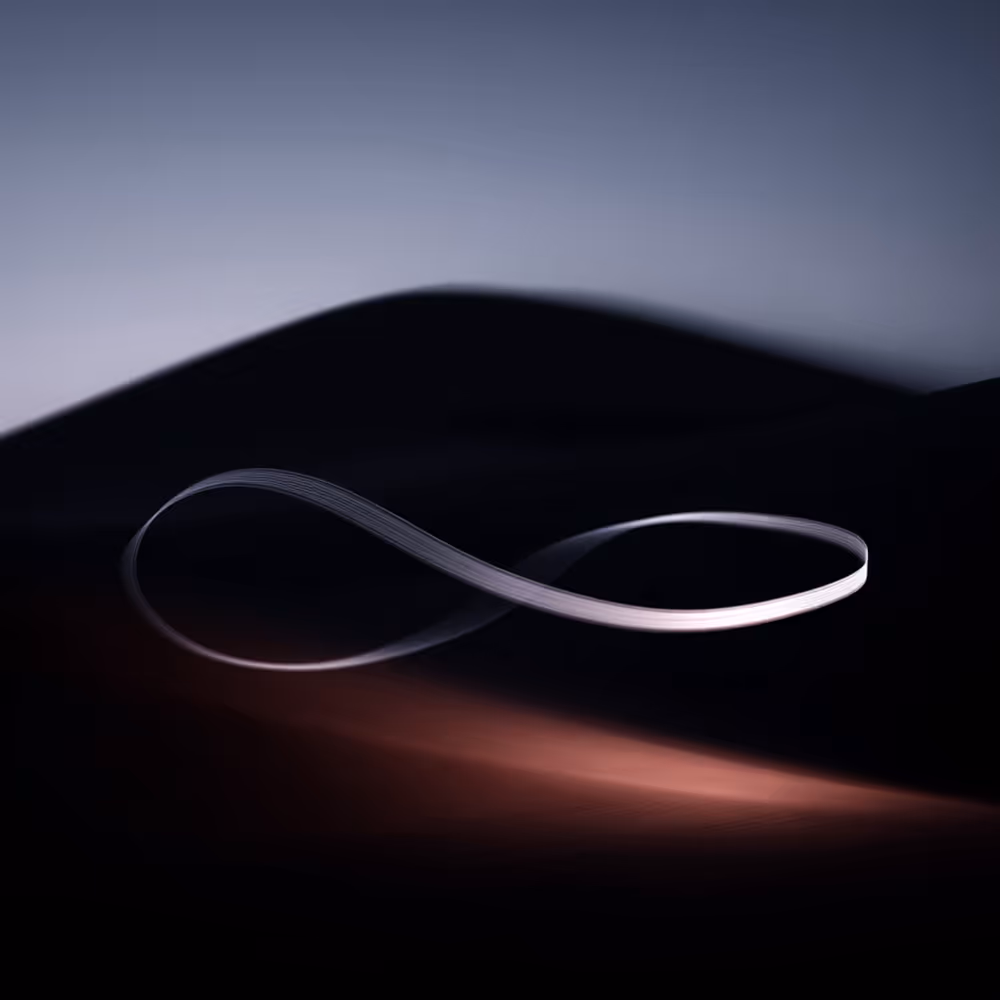 Silver ribbon twisted into an infinity symbol against a dark, softly lit gradient background.