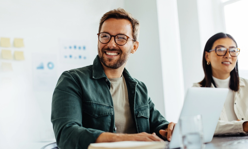 Smiling man in a meeting with a woman in front of a laptop