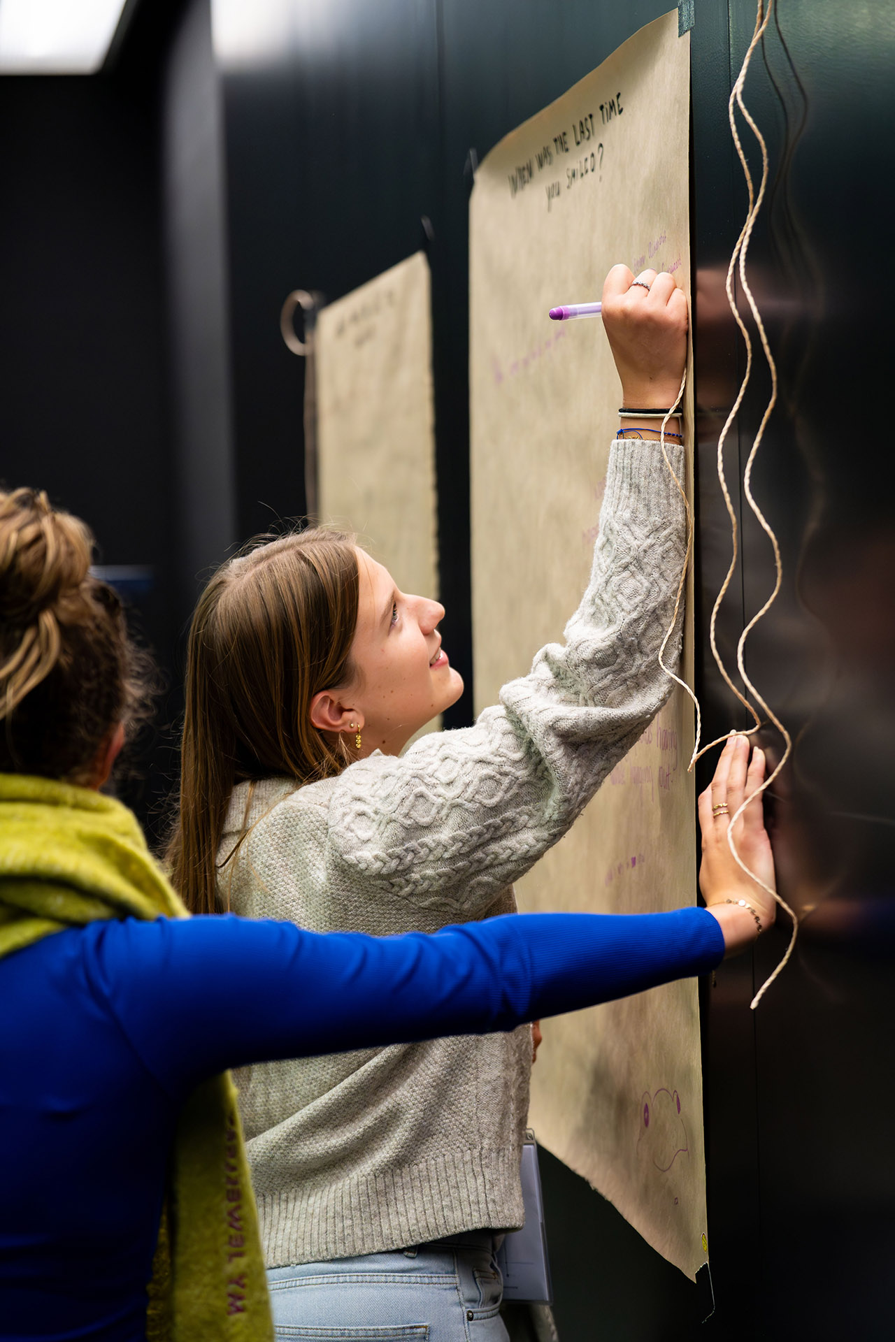 Studenten enthousiast bezig met een project dat op de muur hangt
