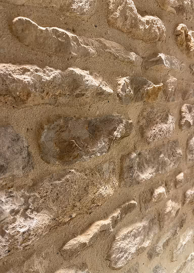 Close-up view of a textured stone wall with lime mortar repointing.