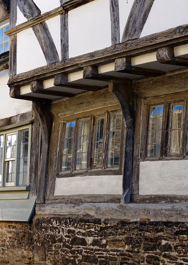 Close-up of weathered timber framing and windows on a historic half-timbered building.