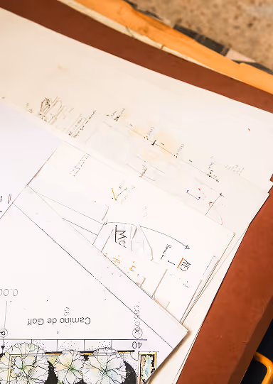 Architectural blueprints and plans spread out on a wooden table.
