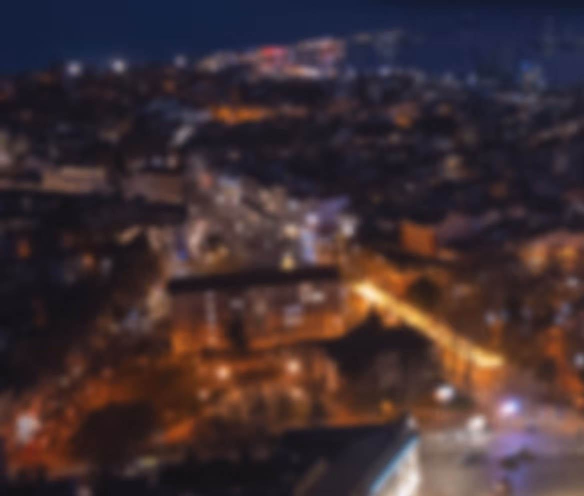 Blurry aerial view of a city at night with illuminated streets and buildings.