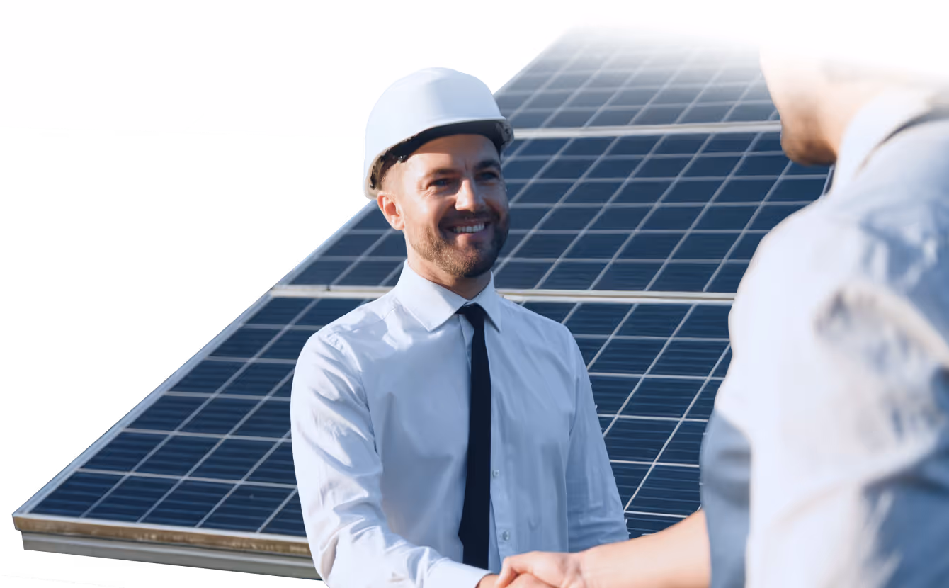 Engineer wearing a white hard hat shaking hands with another person in front of solar panels.