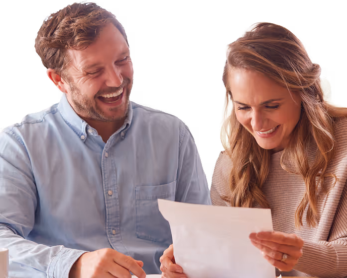 Smiling man and woman looking at a document together.