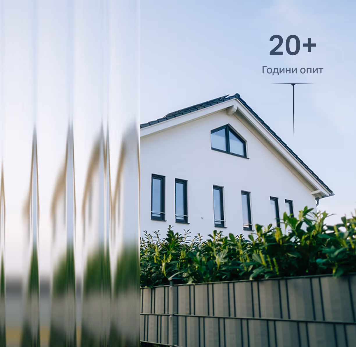 Modern white house with black-framed windows behind green shrubs and a metal fence, with text indicating 20+ years of experience.