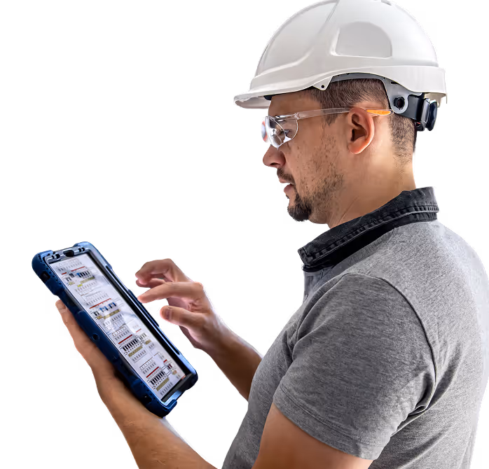 Construction worker wearing a white hard hat and safety glasses using a digital tablet with technical data on screen.