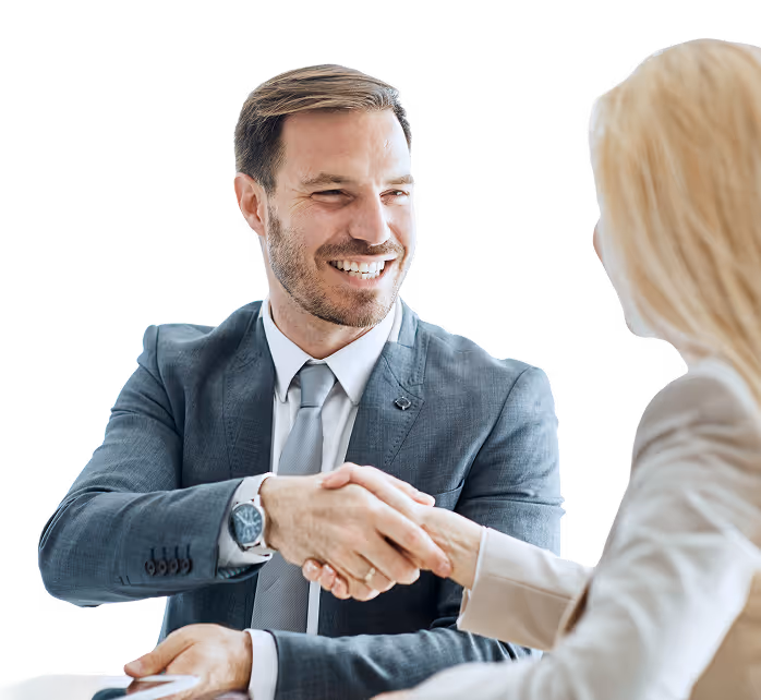 Man in a suit smiling and shaking hands with a woman in a beige blazer.