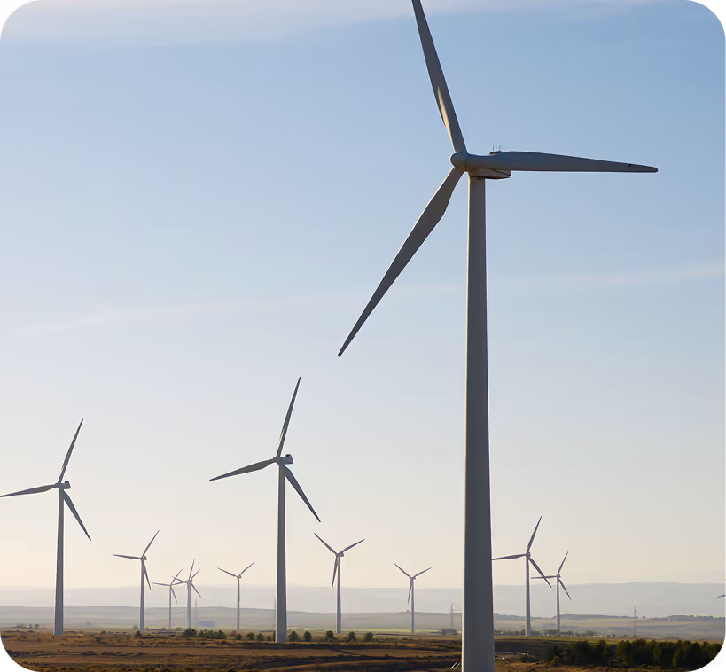 Multiple wind turbines in a dry field under a clear sky during daylight.