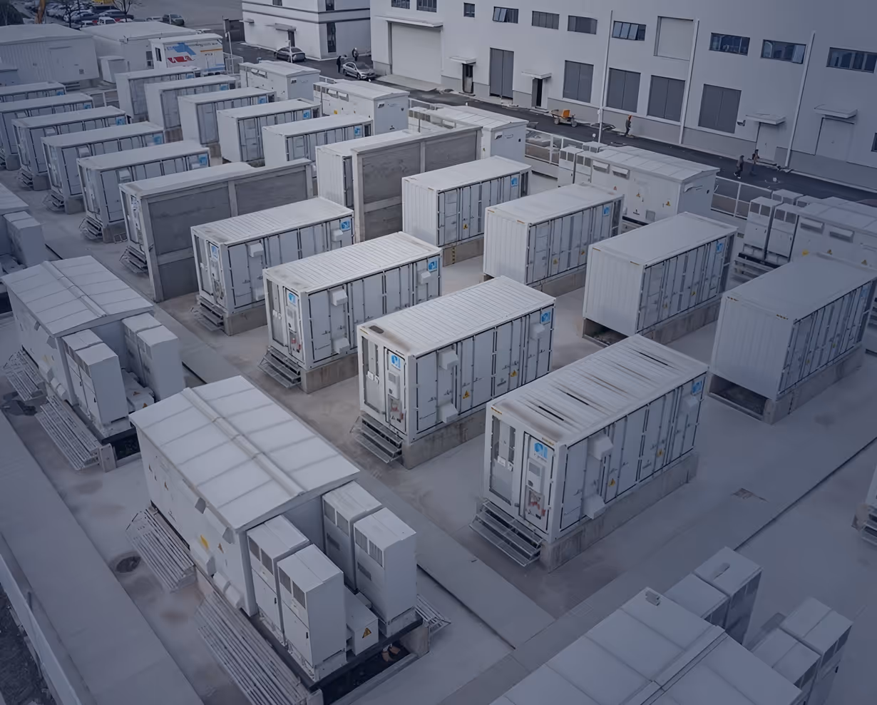 Aerial view of multiple large industrial electrical or HVAC units arranged outdoors near a building.