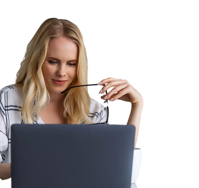 Blonde woman holding glasses while looking at a laptop screen.