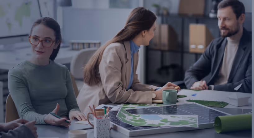 Three colleagues discussing a solar panel and green energy plans in an office setting.