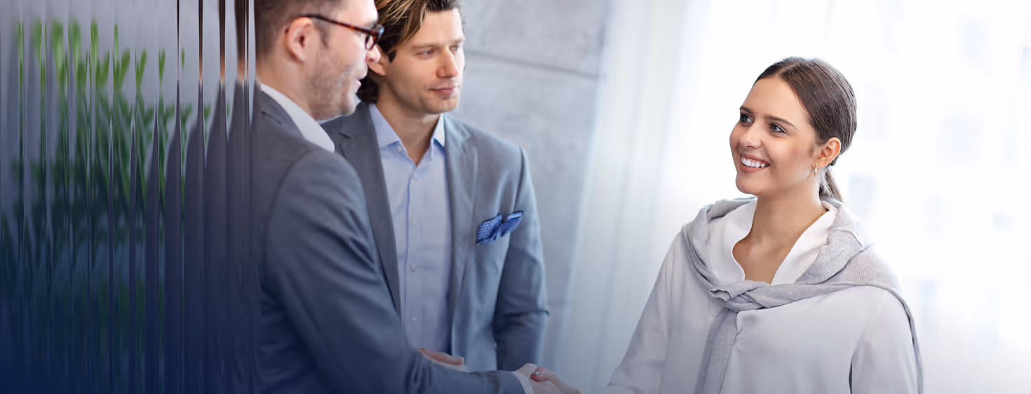 Professional businesswoman shaking hands with a man in a suit during a meeting.