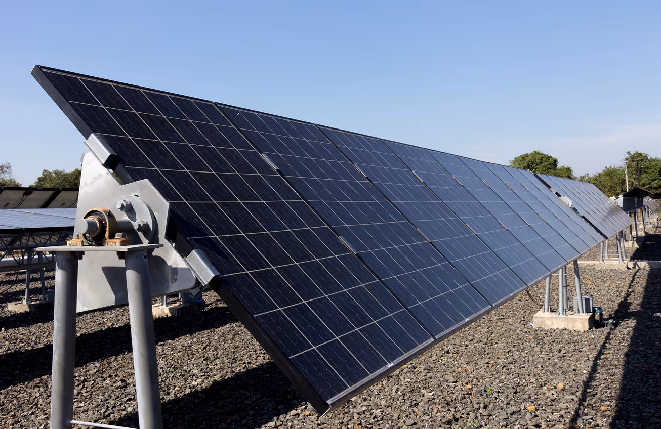 Close-up of a solar panel array tilted on metal supports under a clear blue sky.