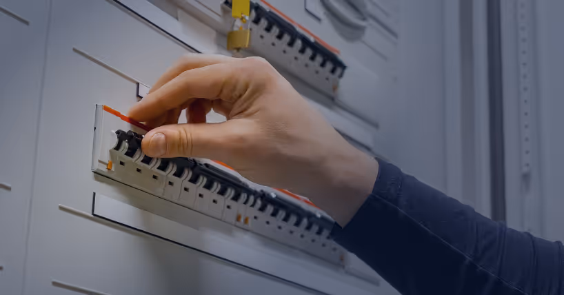 Hand adjusting a circuit breaker switch on an electrical panel.