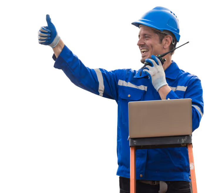 Smiling worker in blue safety gear and helmet giving a thumbs up while holding a walkie-talkie and standing behind a laptop on an orange ladder.
